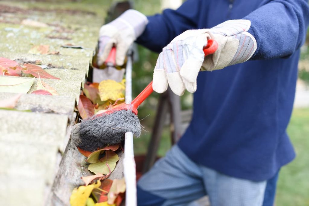 Brushing leaves out of a gutter